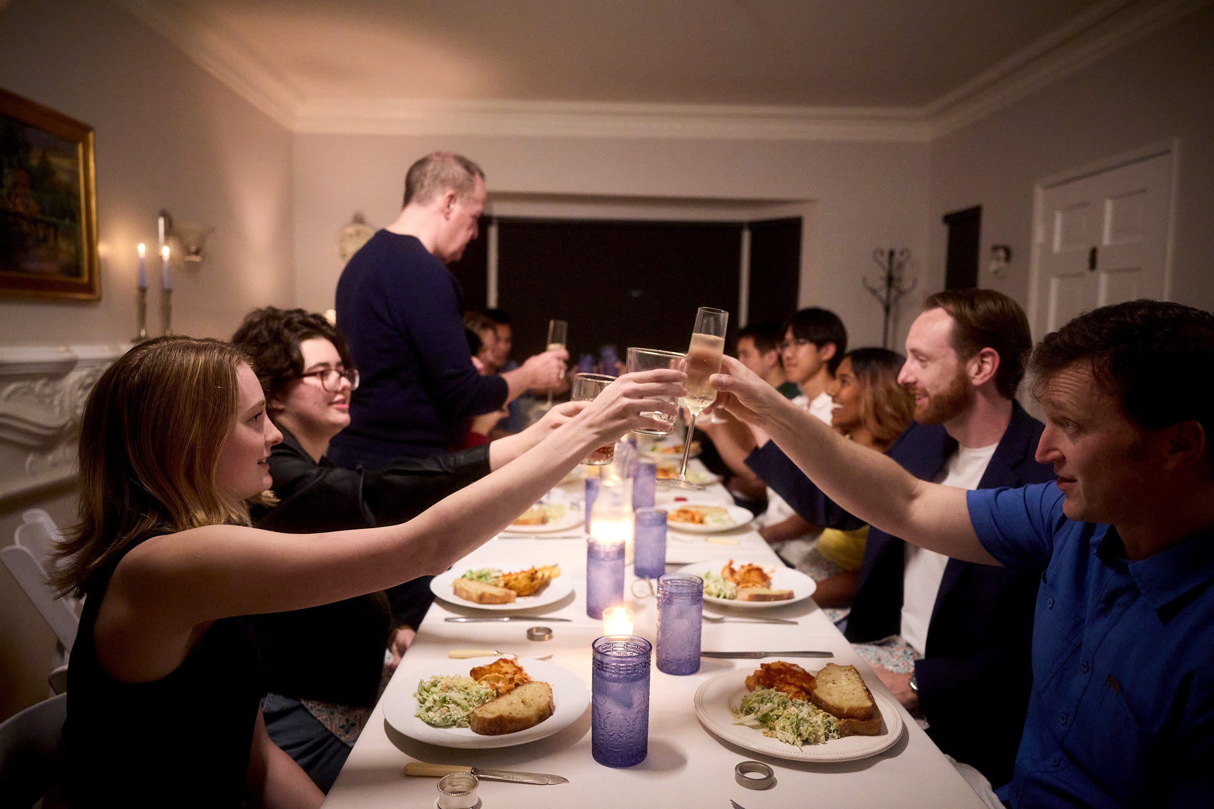 A group of people raising their glasses in a toast at a festive dinner table, celebrating together.