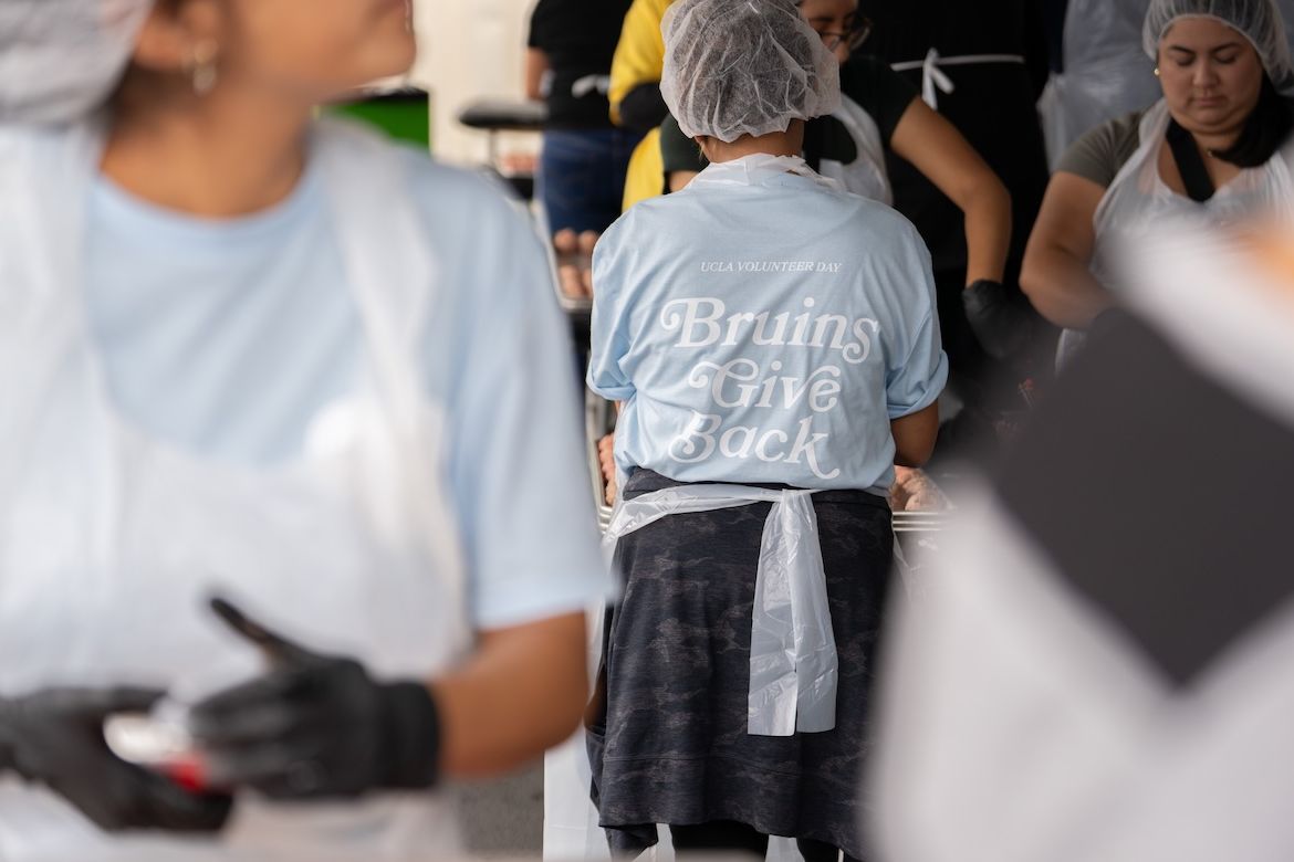 Person pictured from behind wearing hairnet and light blue Bruins Give Back T-shirt at Hope the Mission