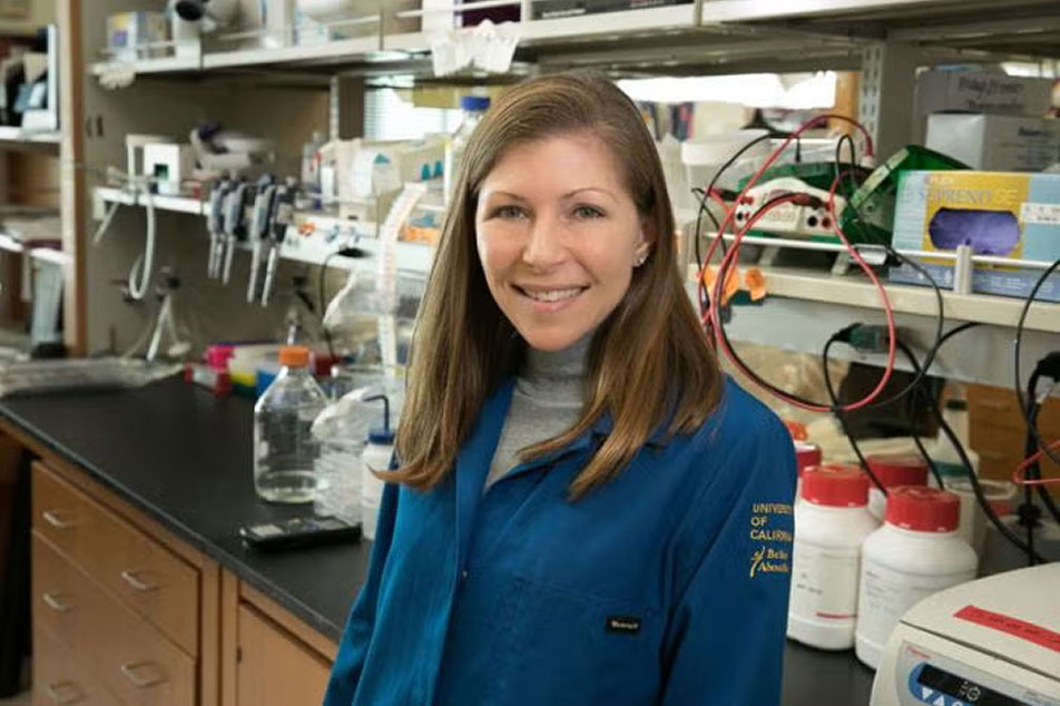 Heather Christofk wearing blue lab coat in front of medical supplies.