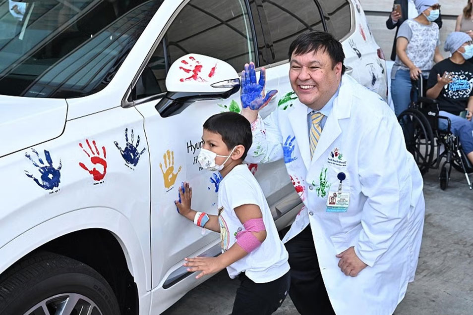 Steve Jonas and a child with painted hands next to a car with hand prints